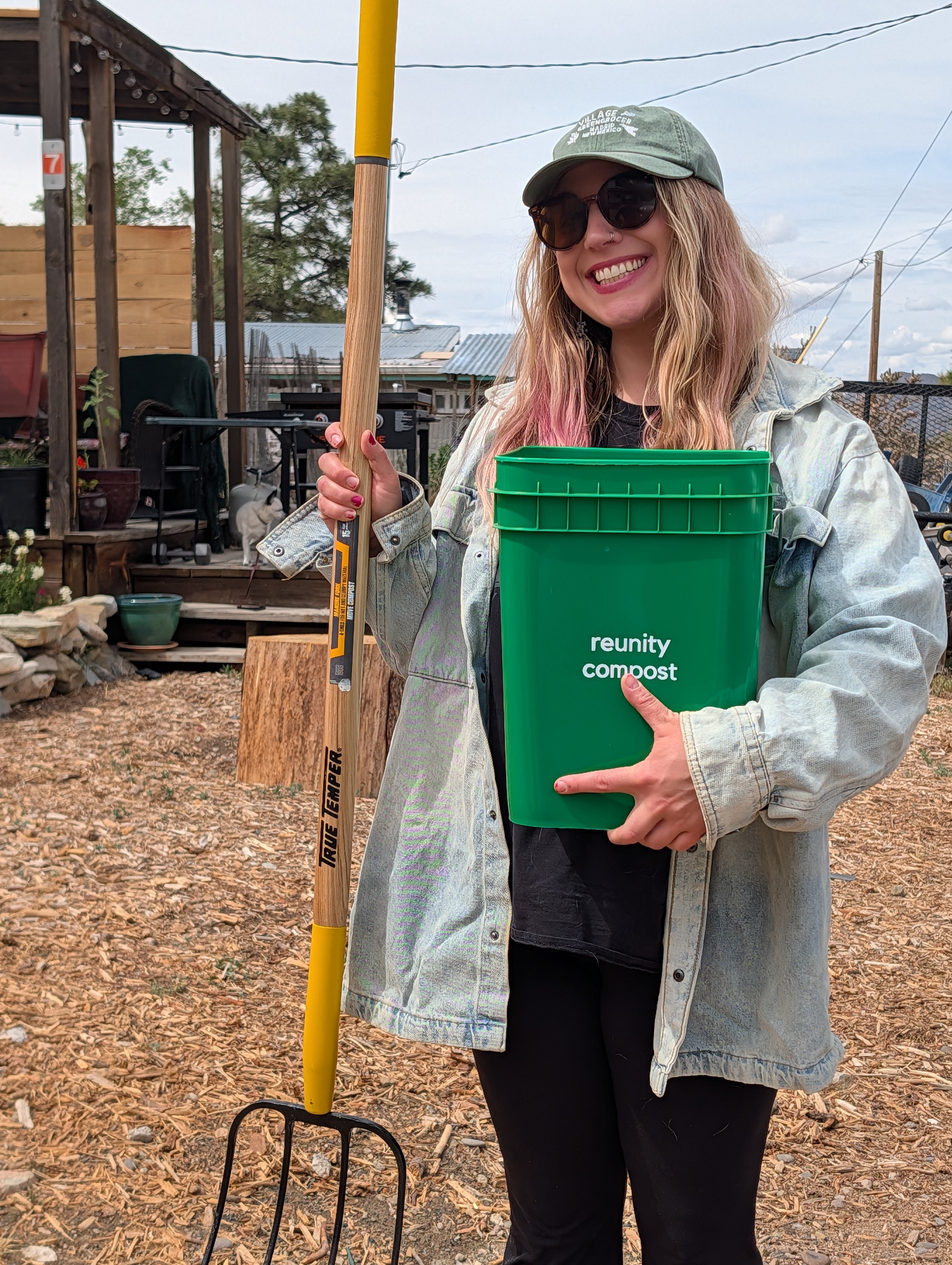 Kate Finio shows off two important tools of composting: a kitchen bucket to collect scraps and a pitchfork to turn and aerate the compost pile.