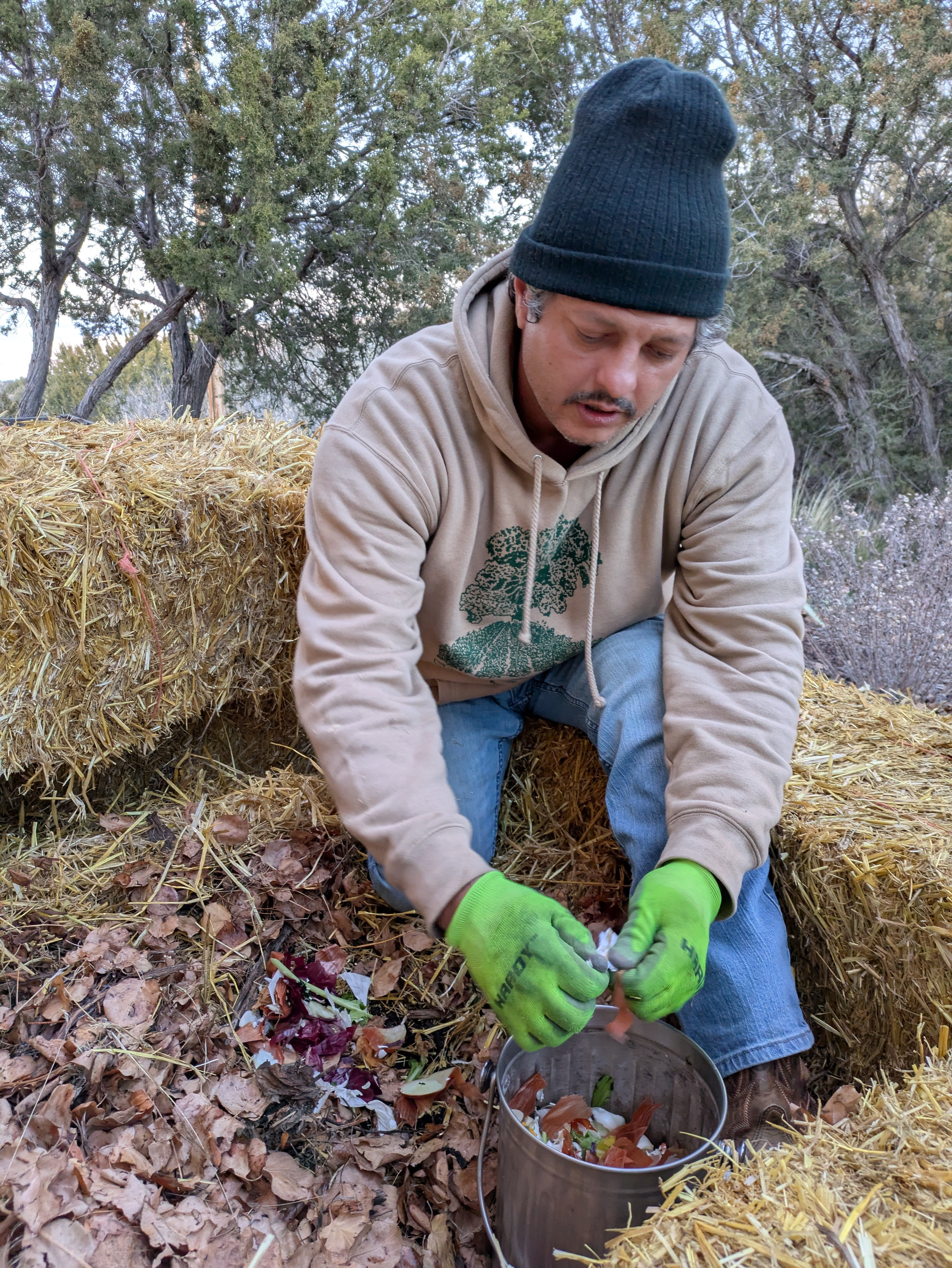 Reunity Resources staff member Mihai Tomozei shows how to add food scraps to a strawbale compost system.