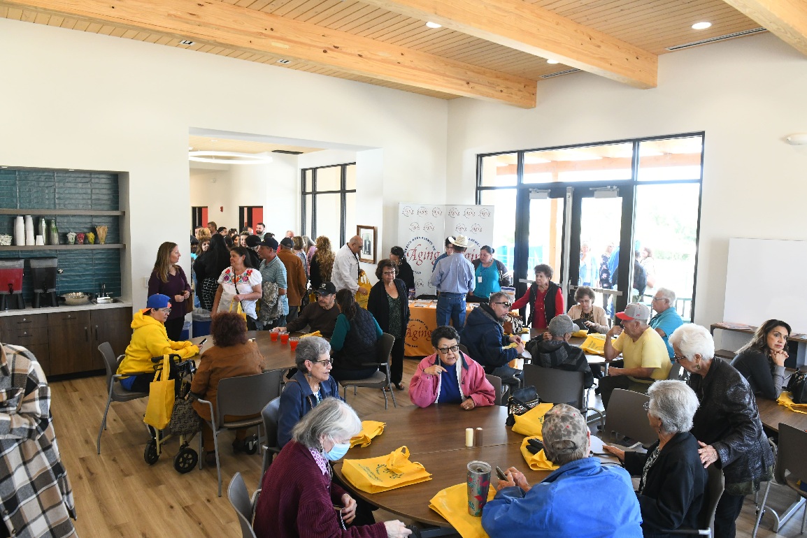 Seniors and staff visiting in the remodeled common area with new seating and natural light.