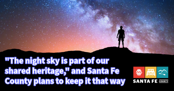A person in shadow stands against a bright Milky Way backdrop